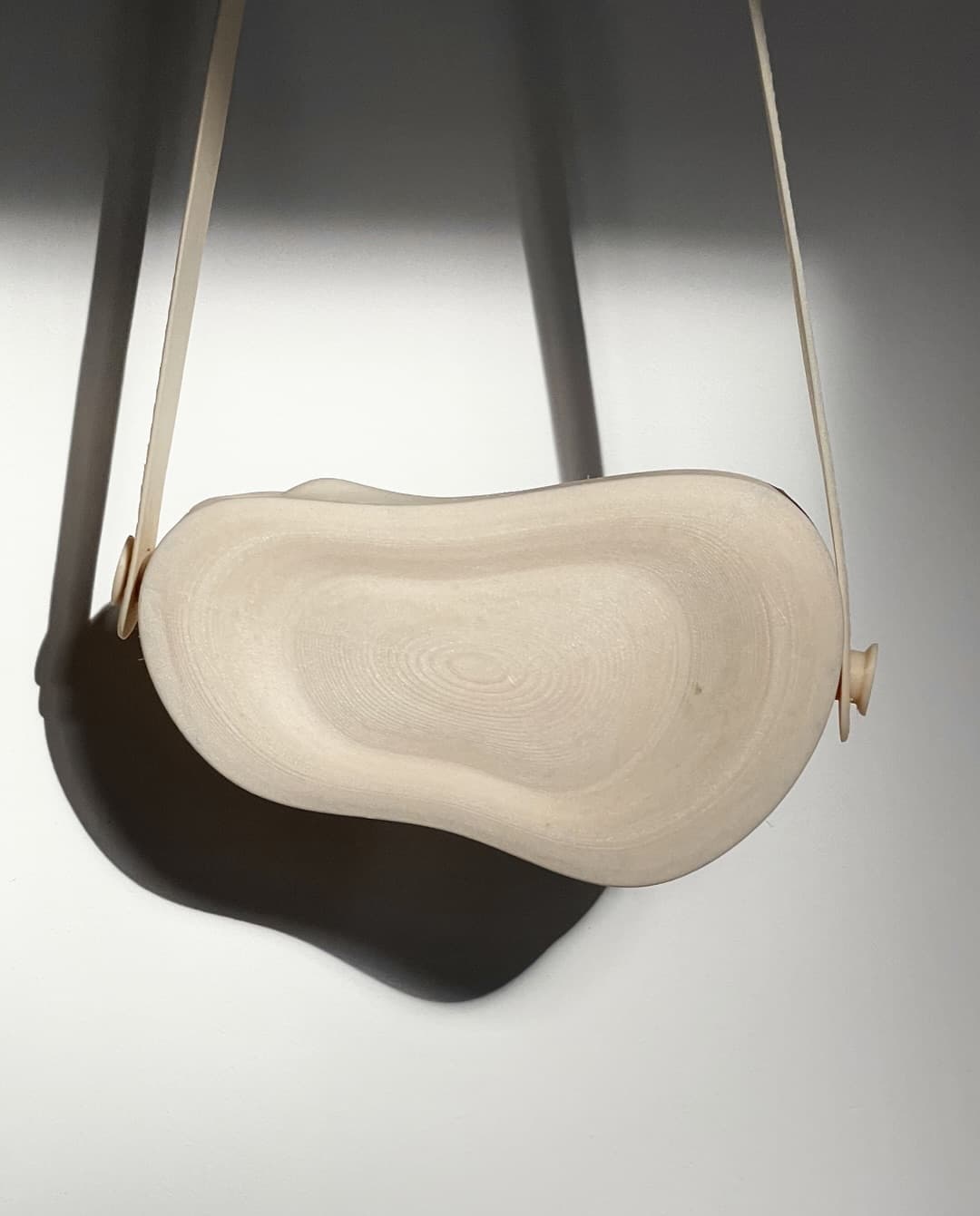 ORRA hanging from its straps against a white wall