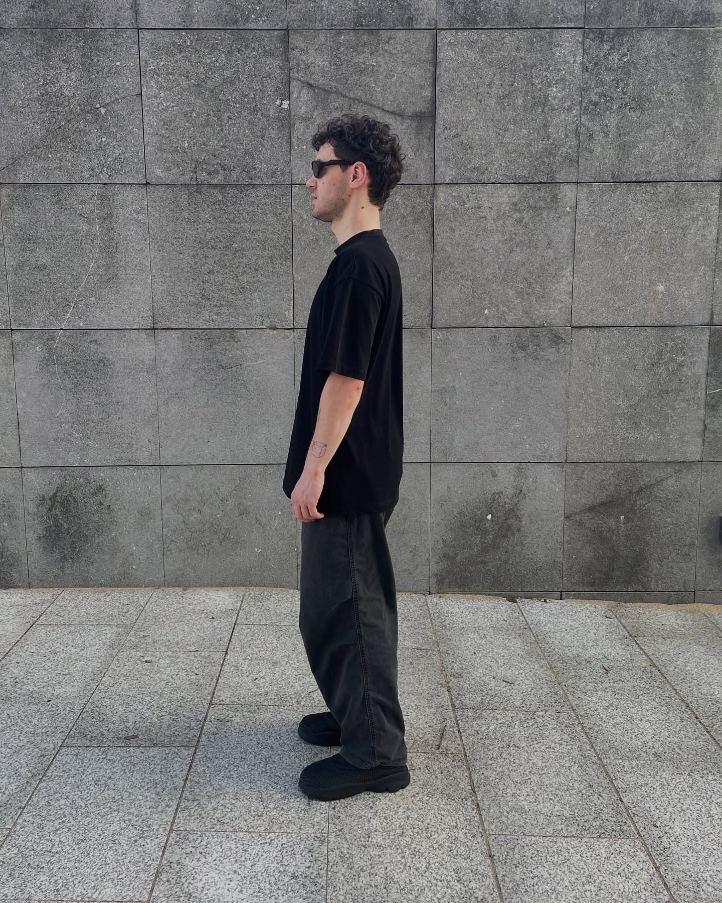 P100 worn in the black colorway, side profile against a stone wall