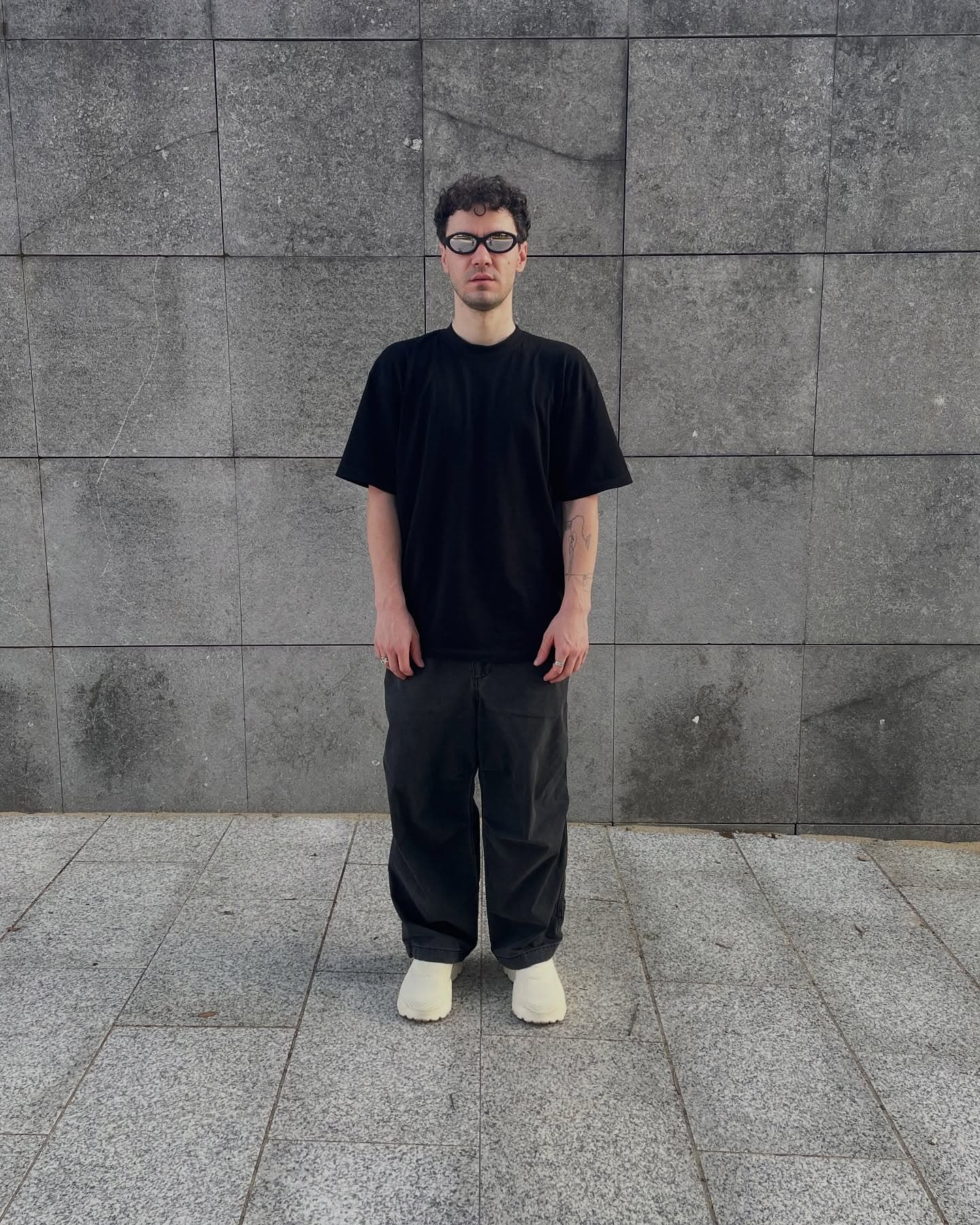 P100 worn in the cream colorway, front-on against a stone wall