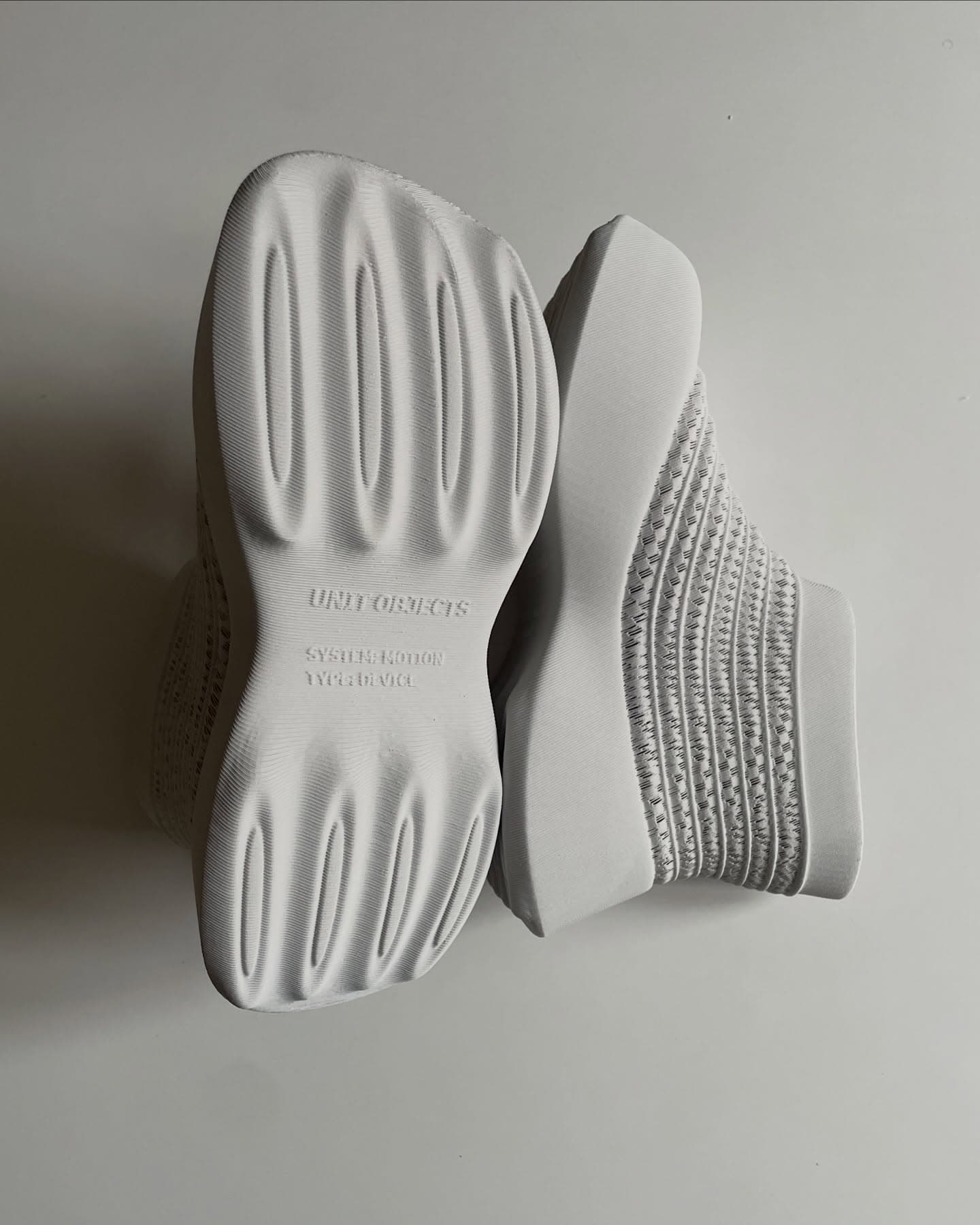 UOMD pair overhead, one flipped showing the outsole debossed with UNIT OBJECTS