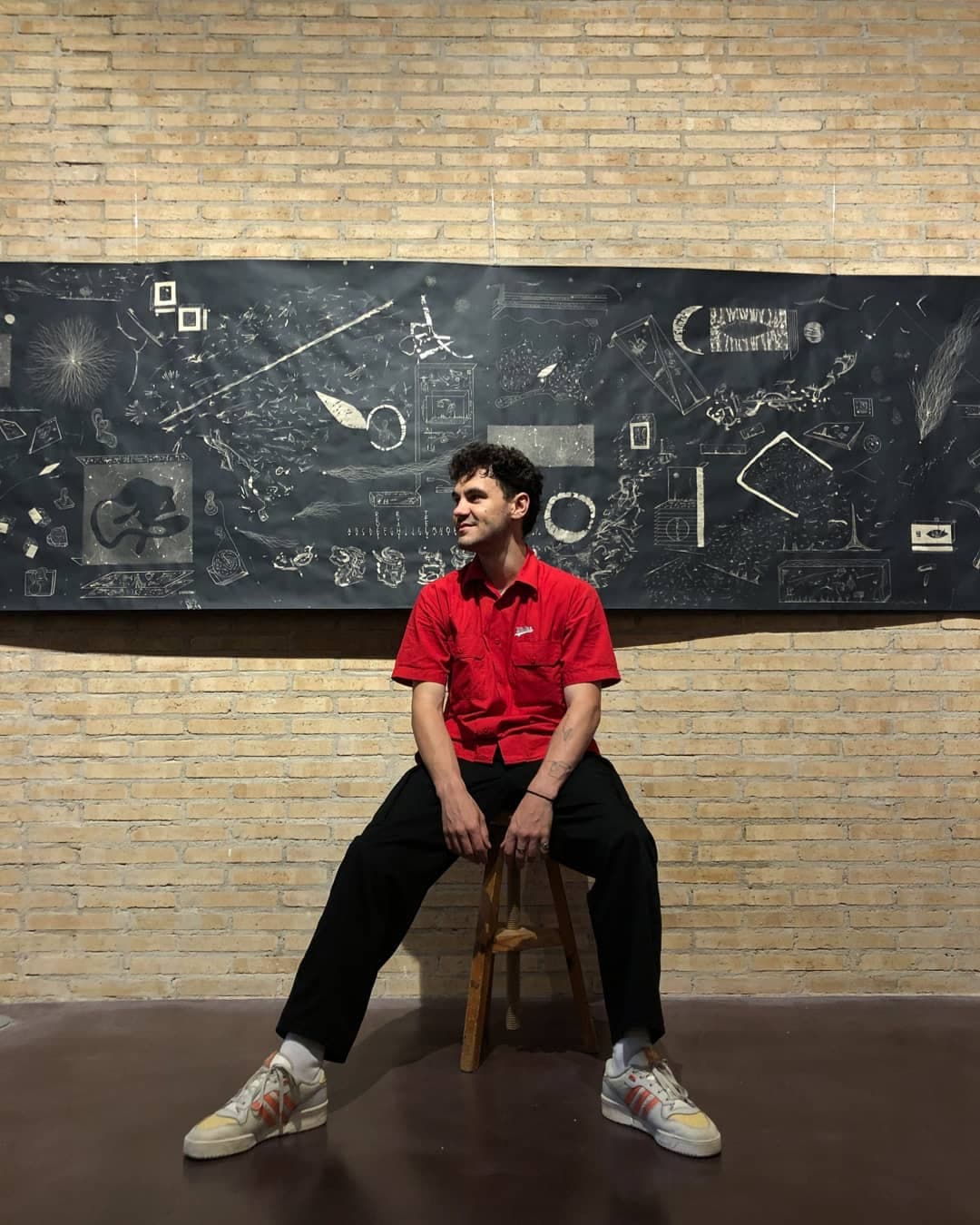 The artist seated in front of the hung panel during the exhibition
