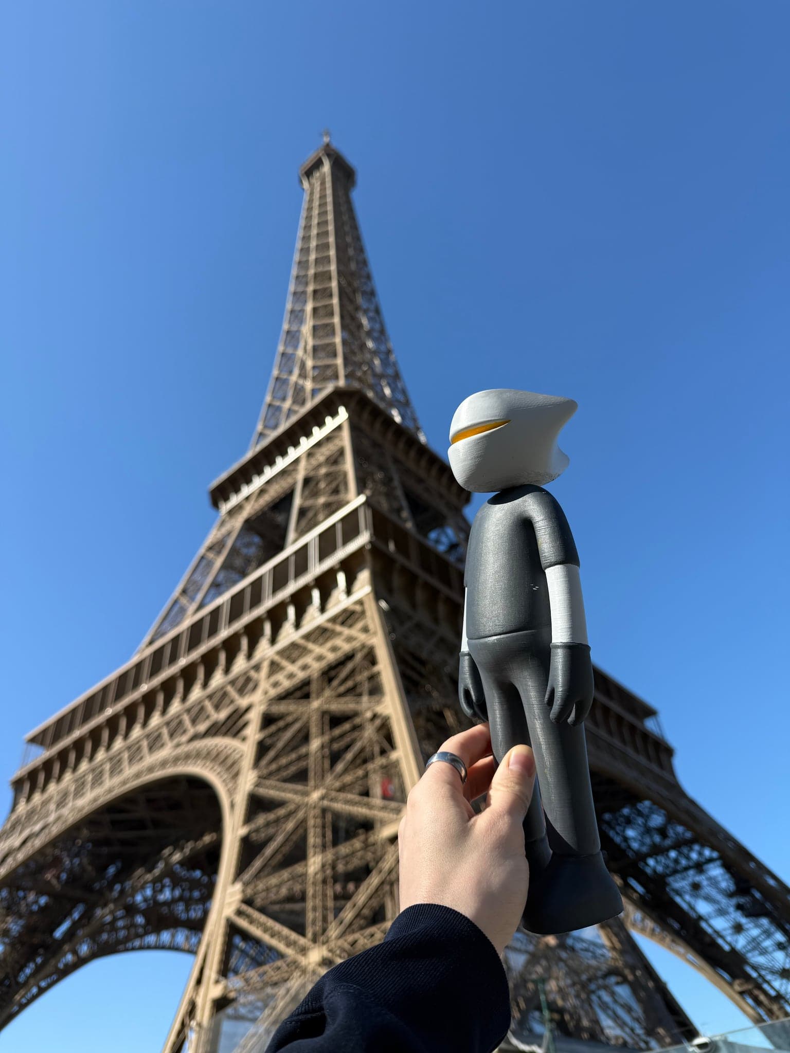 Mr. B turned in the hand so the light catches his hood, the tower behind him