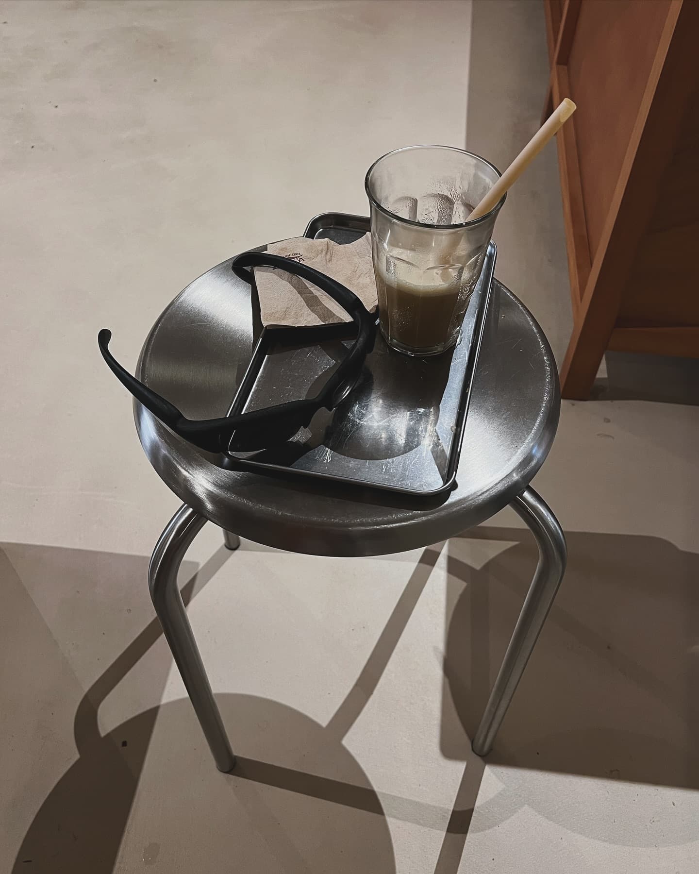 BRUT SHADES resting on a steel stool beside an iced coffee