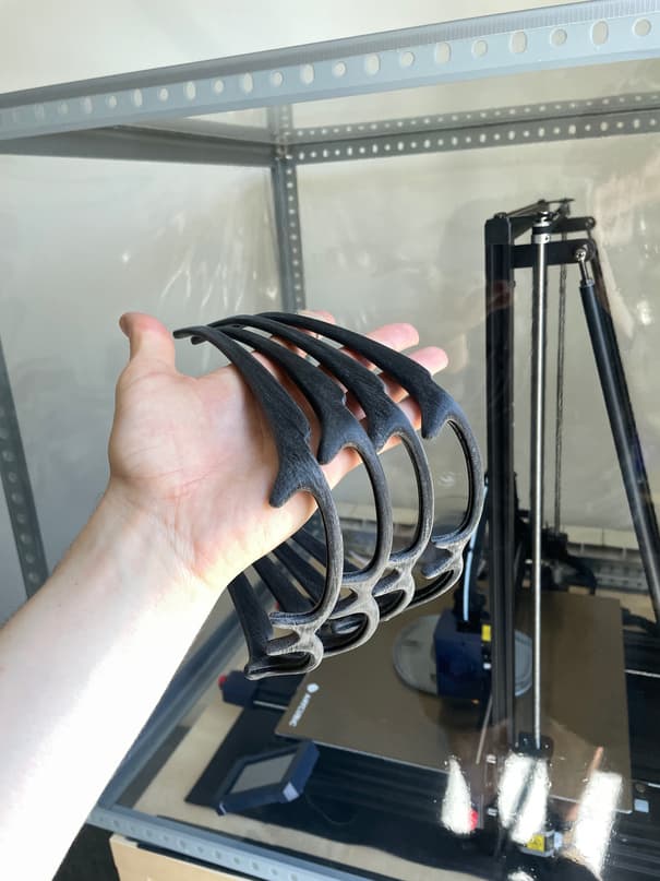 A hand holding four printed frames still nested together, the printer behind
