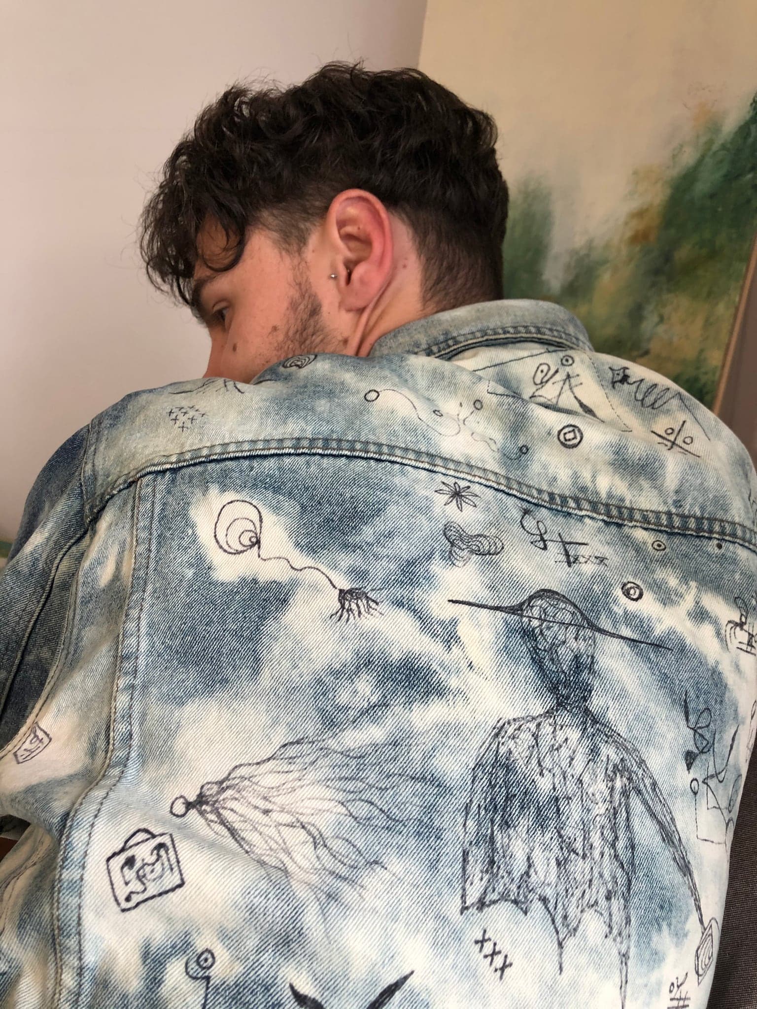 Close on the back of the jacket: a figure throwing off rays, a plant, small framed boxes and an eye drawn in fine dark line over bleached blooms