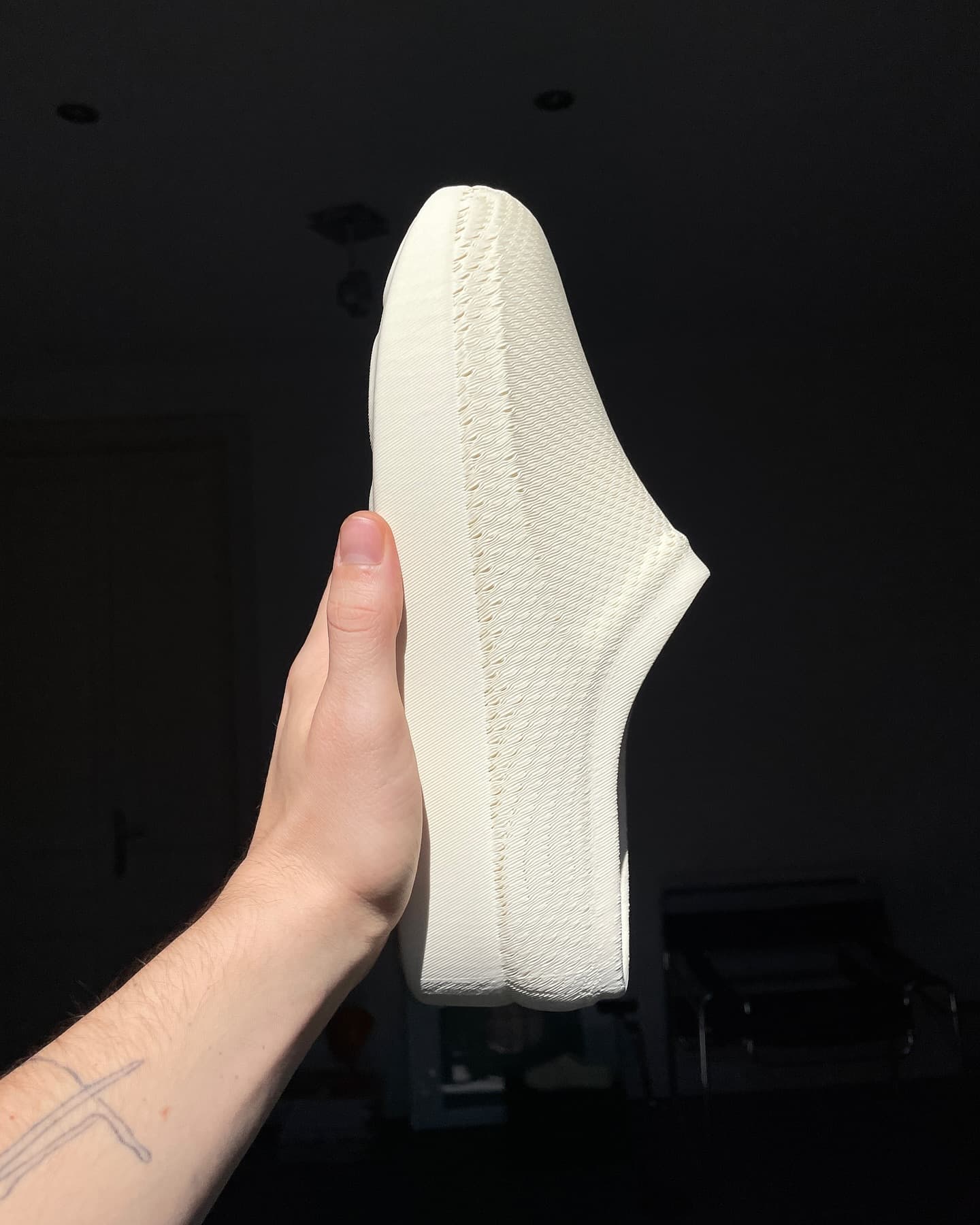 Hand holding CASUL sole-up, showing the ribbed 3D-printed underside