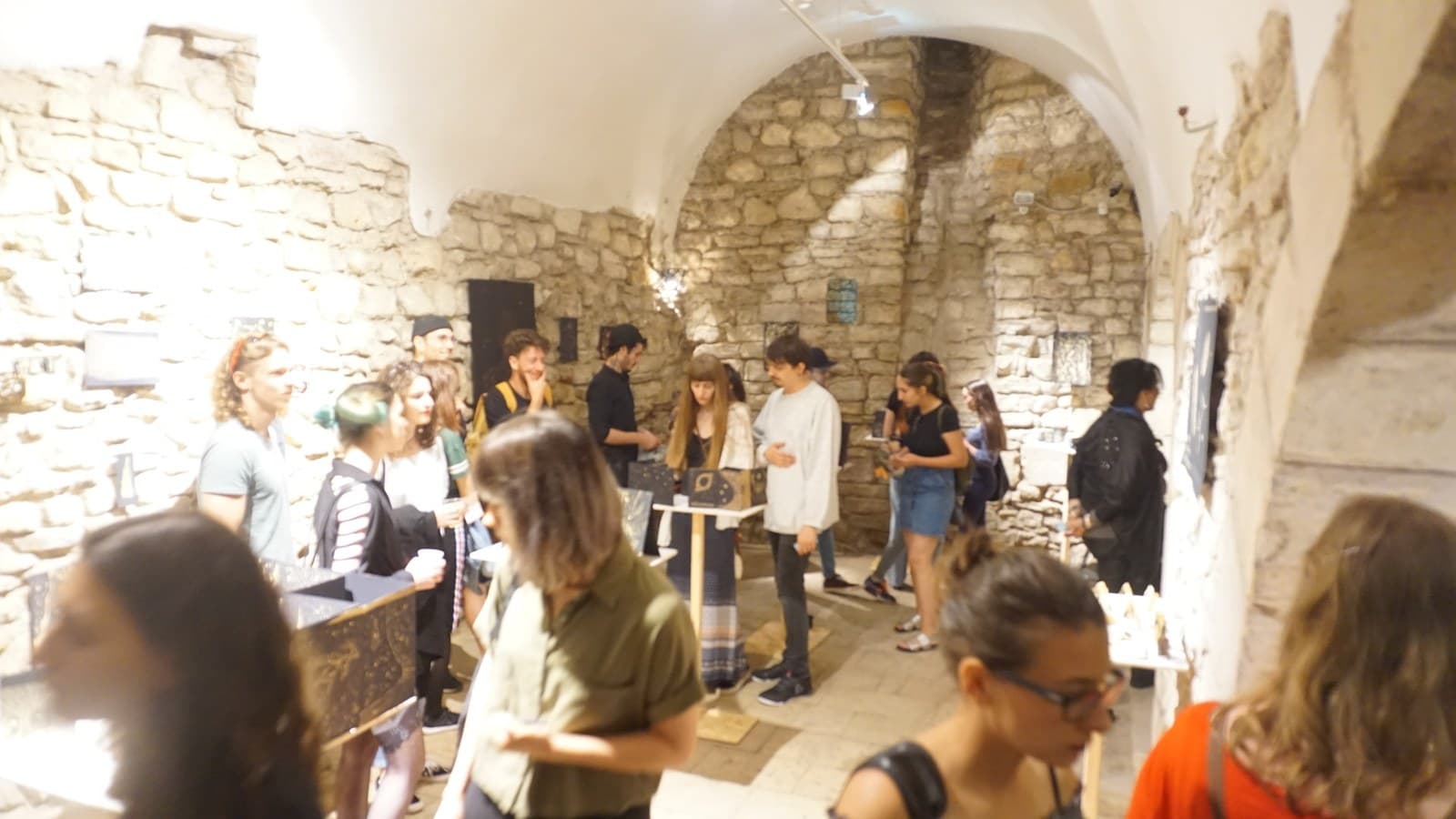 The vaulted room filled with people under the stone arches, works on their plinths standing between them