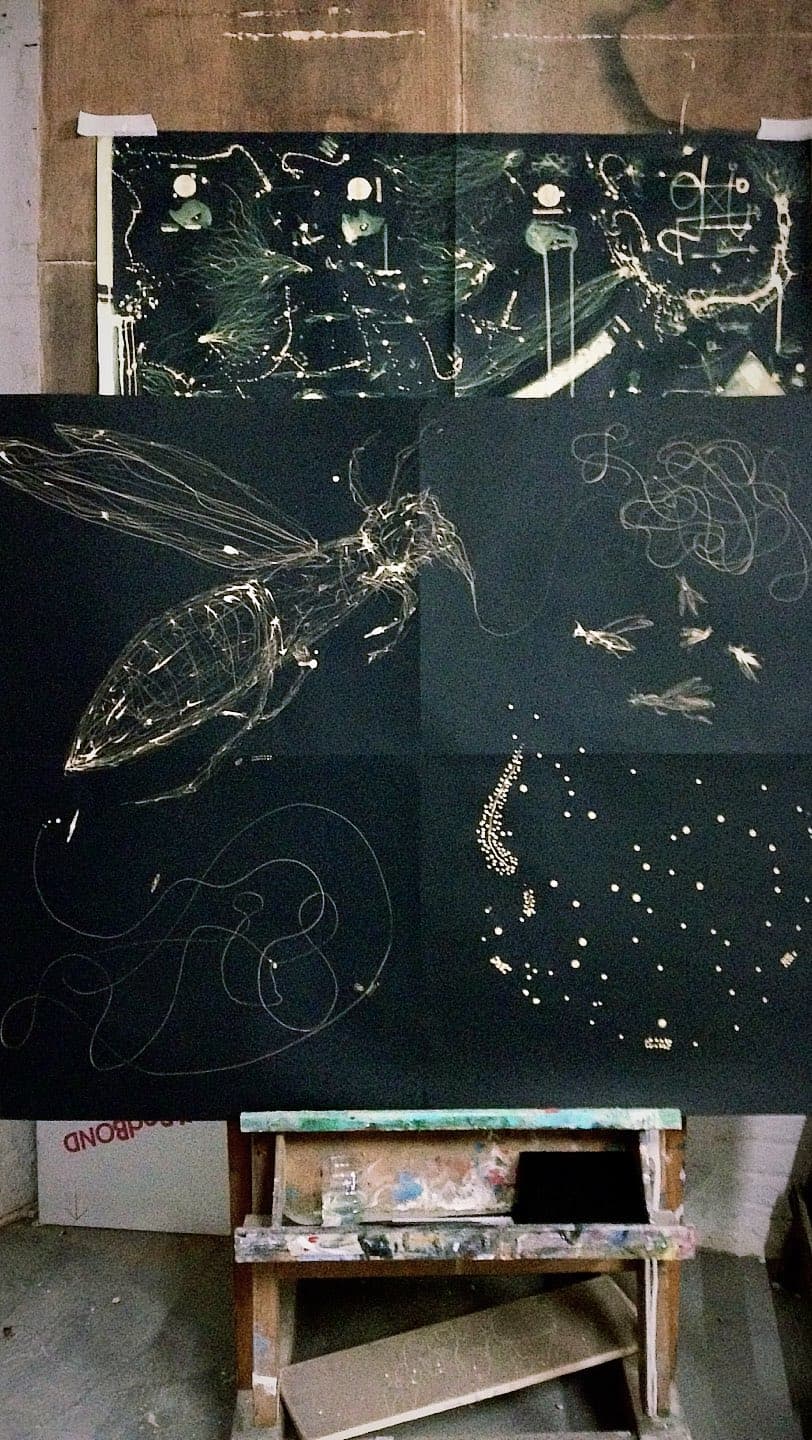 Four bleached sheets pinned together on a studio wall above a paint spattered bench, one of them the winged form