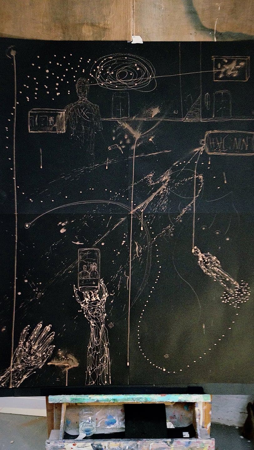 A sheet on the wall carrying hands, a figure and scattered dotted lines, the workbench below it