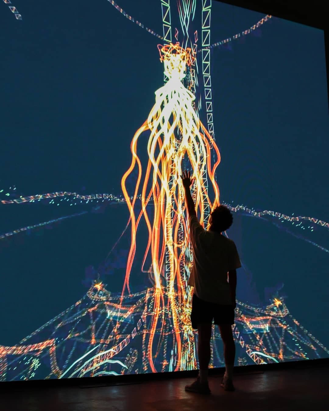 A tall gold column rising through the frame, a figure with one hand raised toward it