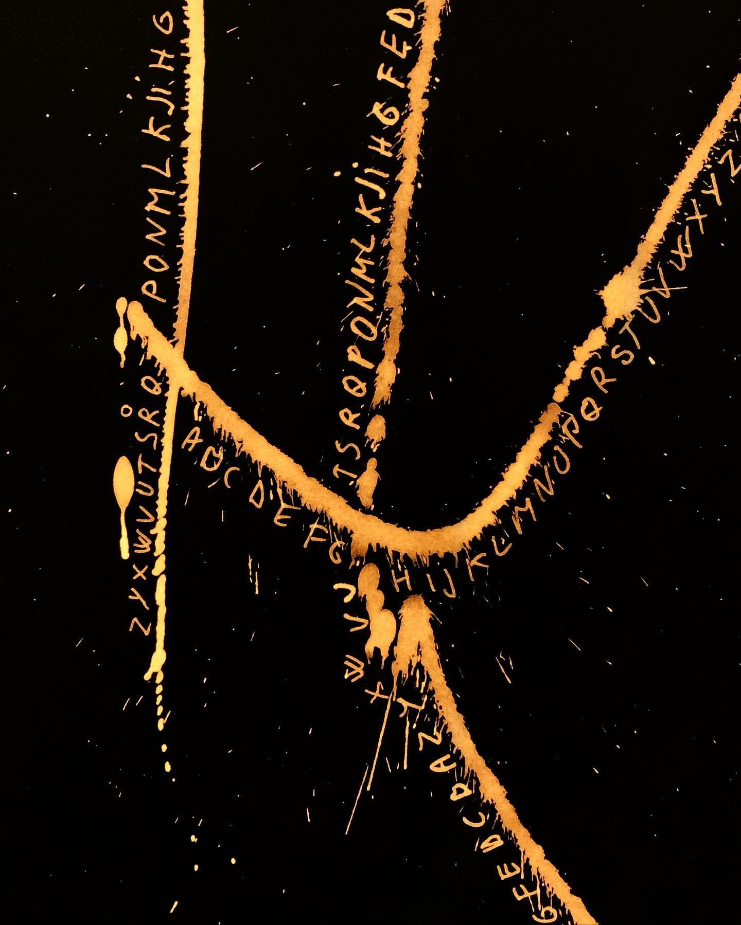 A close view of the sheet, alphabets running in pale gold along two long curving lines