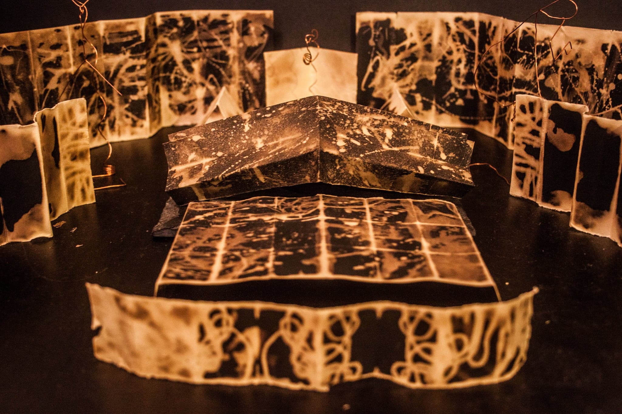 The same arrangement from lower down, the books standing in a ring around one spread laid flat at the centre.