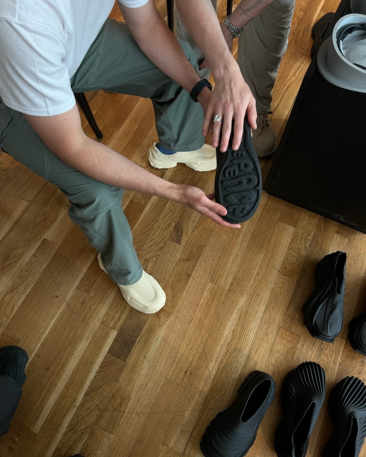 Hands turning over a Pioneer sneaker, examining the sole