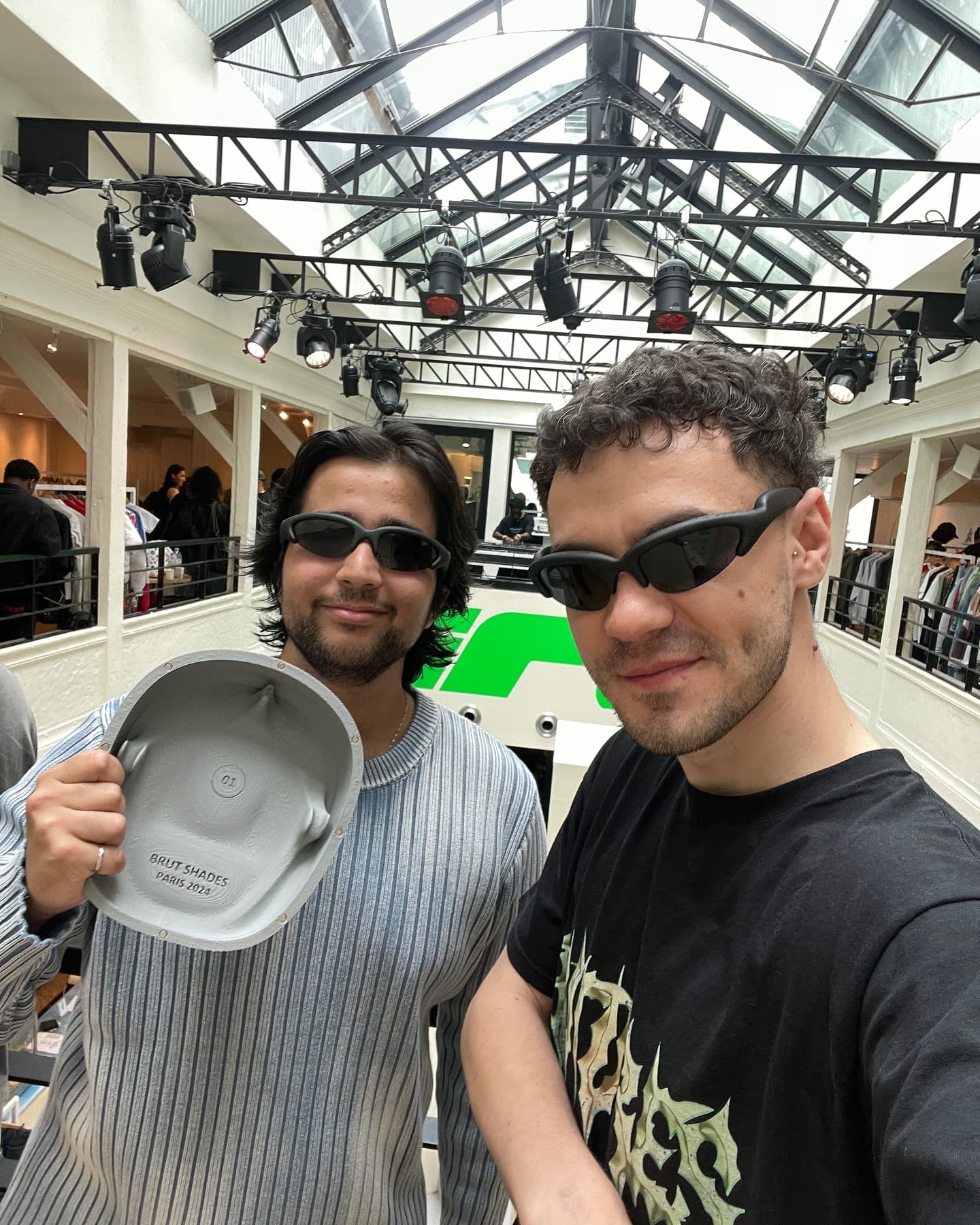Two visitors holding a shoe and wearing the shades, laughing