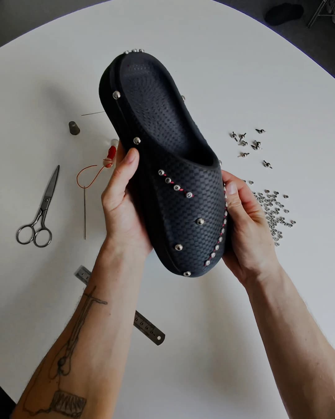 Overhead view of the shoe half studded, a line of metal running from the toe back along the flank, loose studs scattered around it