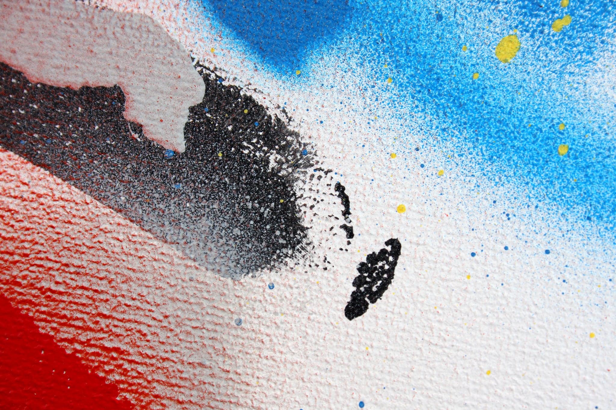 Close view: a dark smear of overspray drifting across blue.