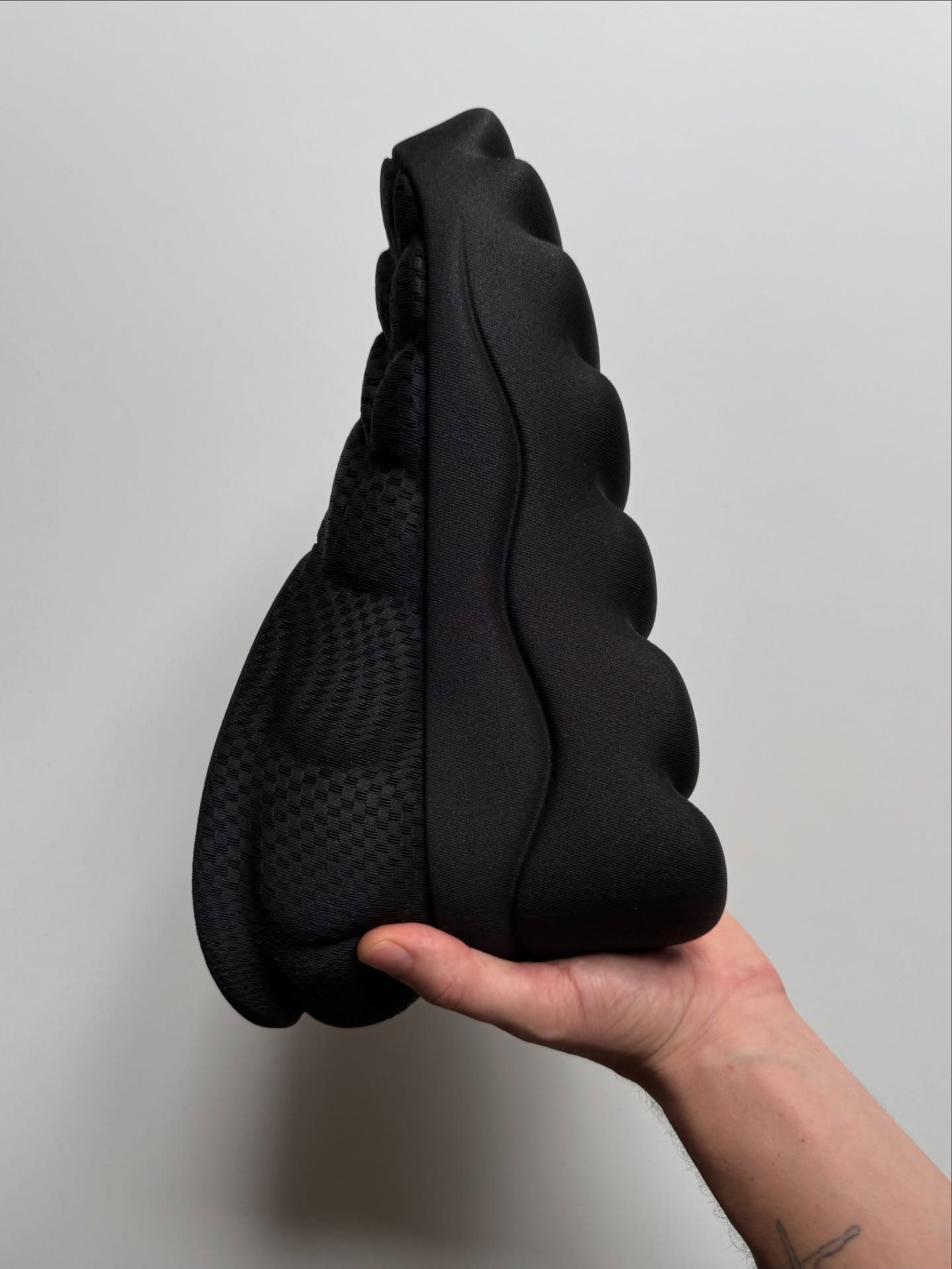 Hand holding the physical SBOOT prototype against a light wall