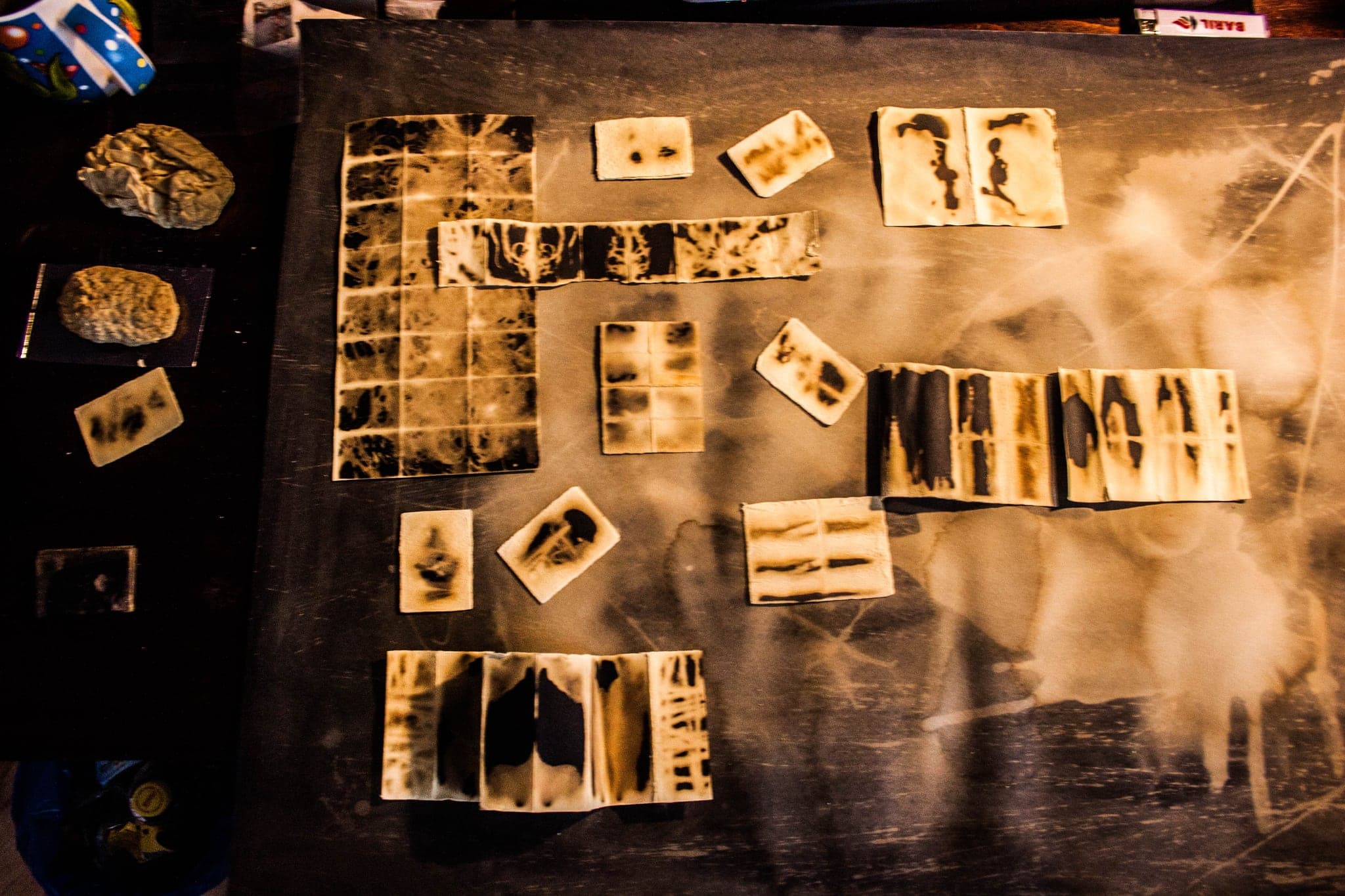 Wax tiles arranged on a dark cloth-covered table in a studio, edges of the room visible at the left.