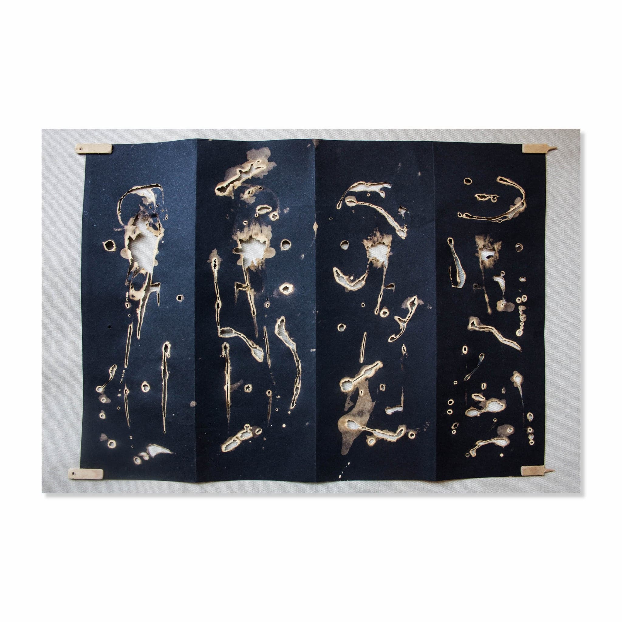 TOTEM II opened out flat, the burned-through marks reading as open holes in the sheet