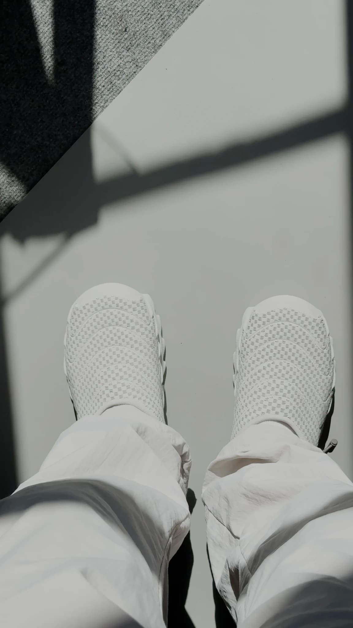 A closer view down at both shoes on the feet, the perforated mesh of the upper clearly visible as a grid