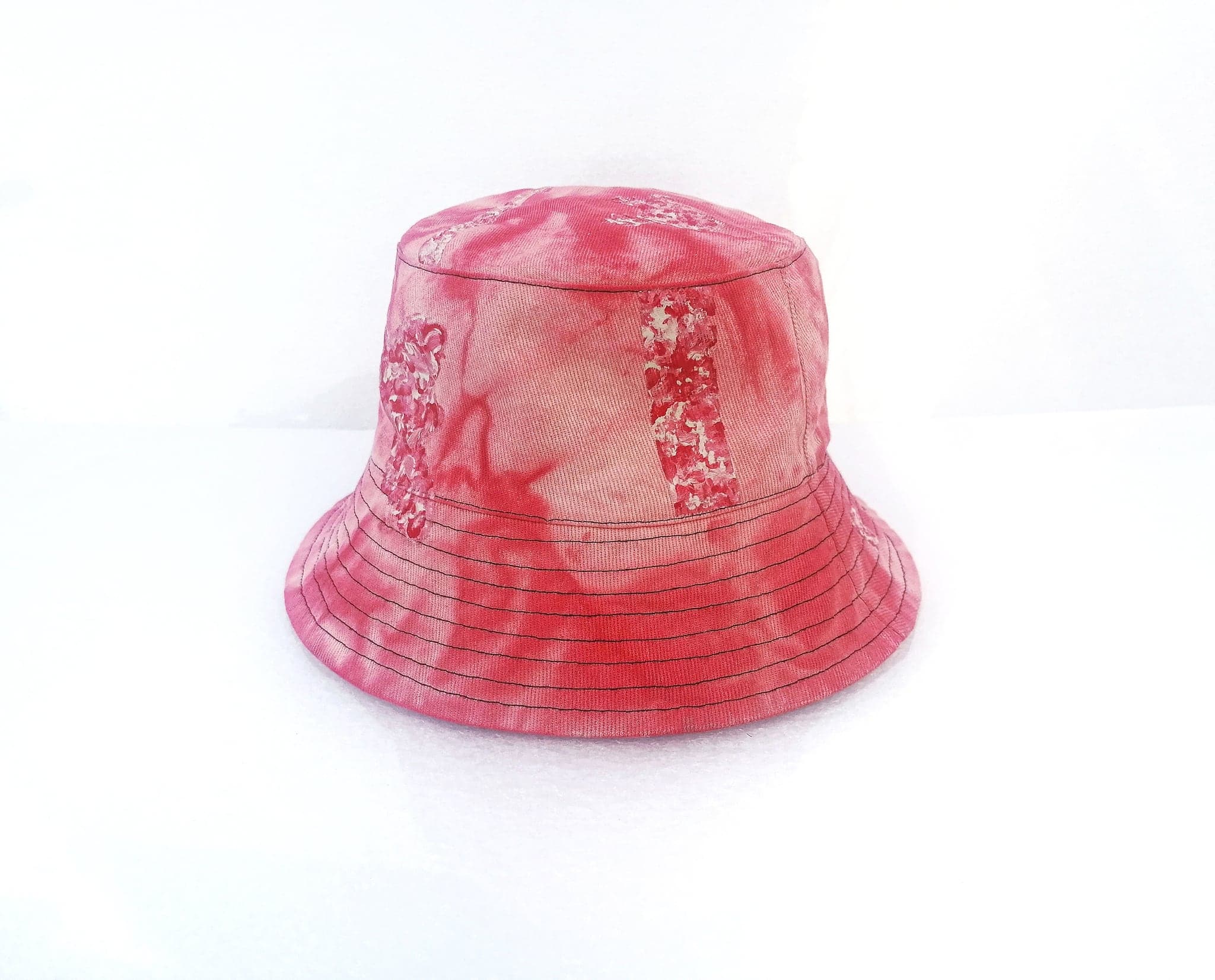 The red hat on a white ground, three quarters on, the brim rings catching the dye unevenly