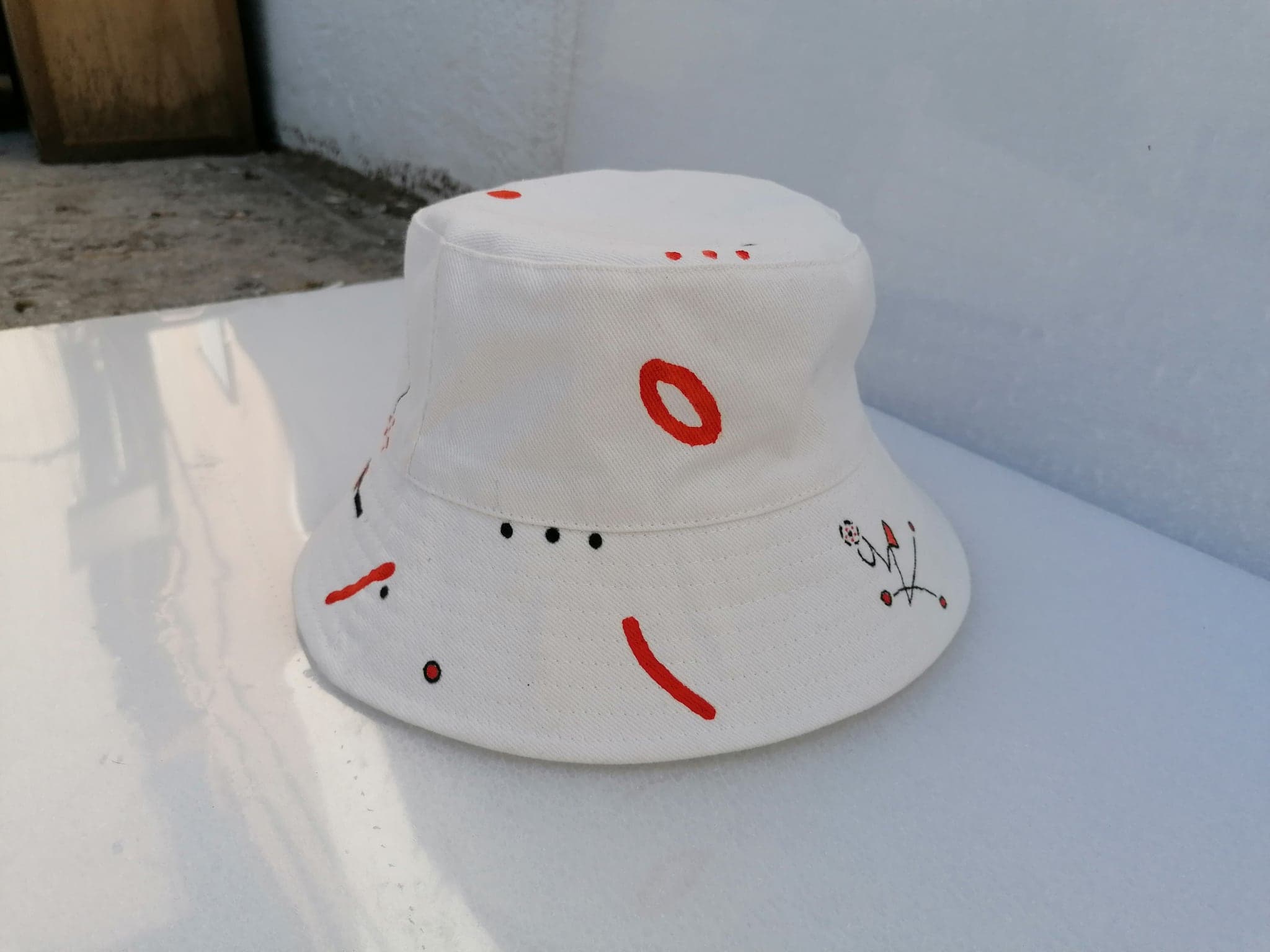 The white hat on the ledge in hard sunlight, its shadow falling across the wall behind